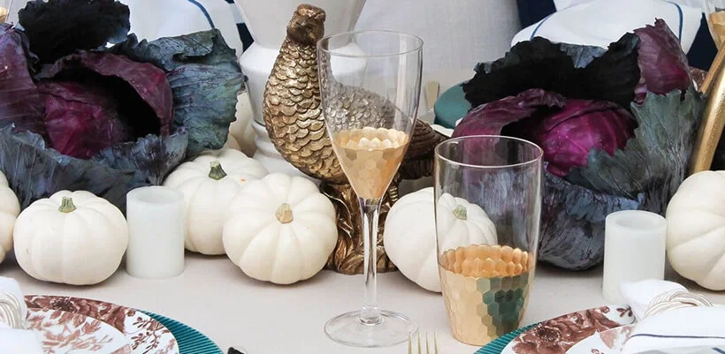 Close up of gold barware with white pumpkins in the background